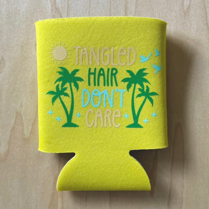 Yellow can cooler with 'Tangled Hair Don't Care' text and palm tree design on a wooden surface