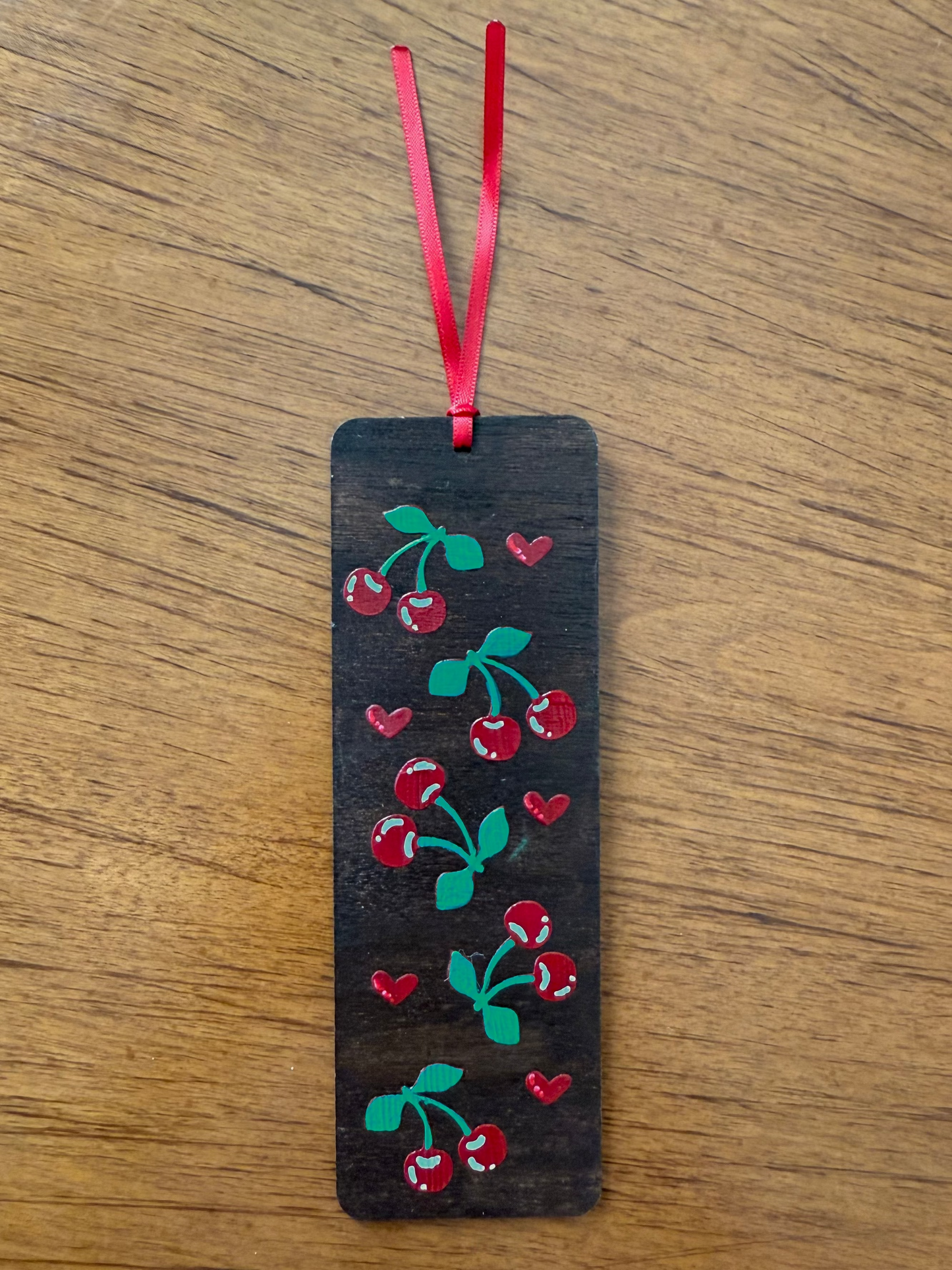 Bookmark with cherry design on a wooden surface
