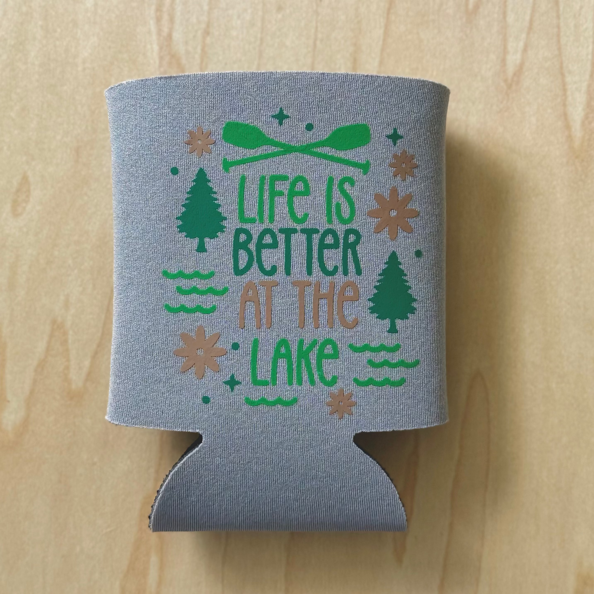 Gray can cooler with 'Life is Better at the Lake' text on a wooden surface