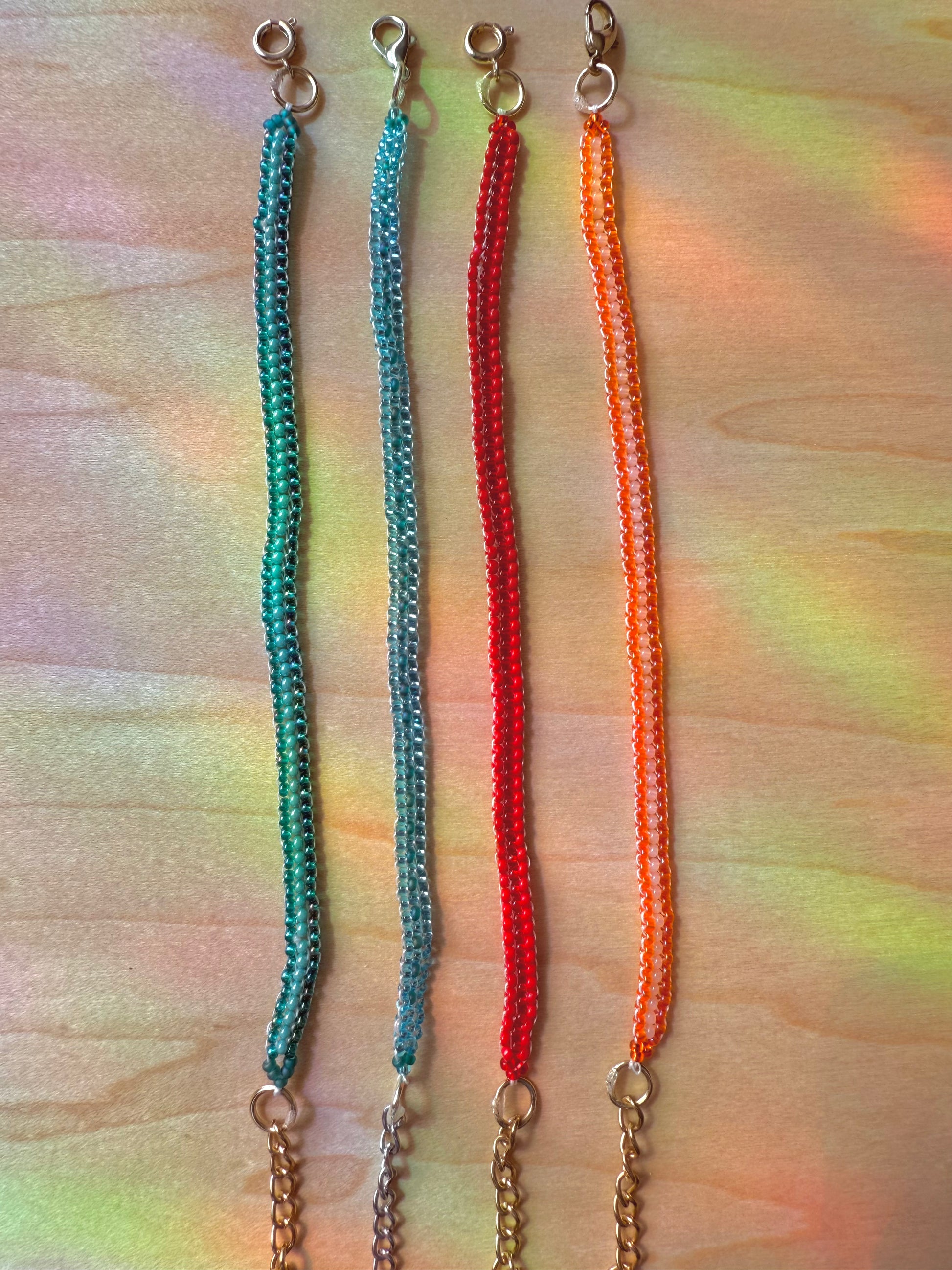 Four colorful beaded lanyards on a multicolored fabric background