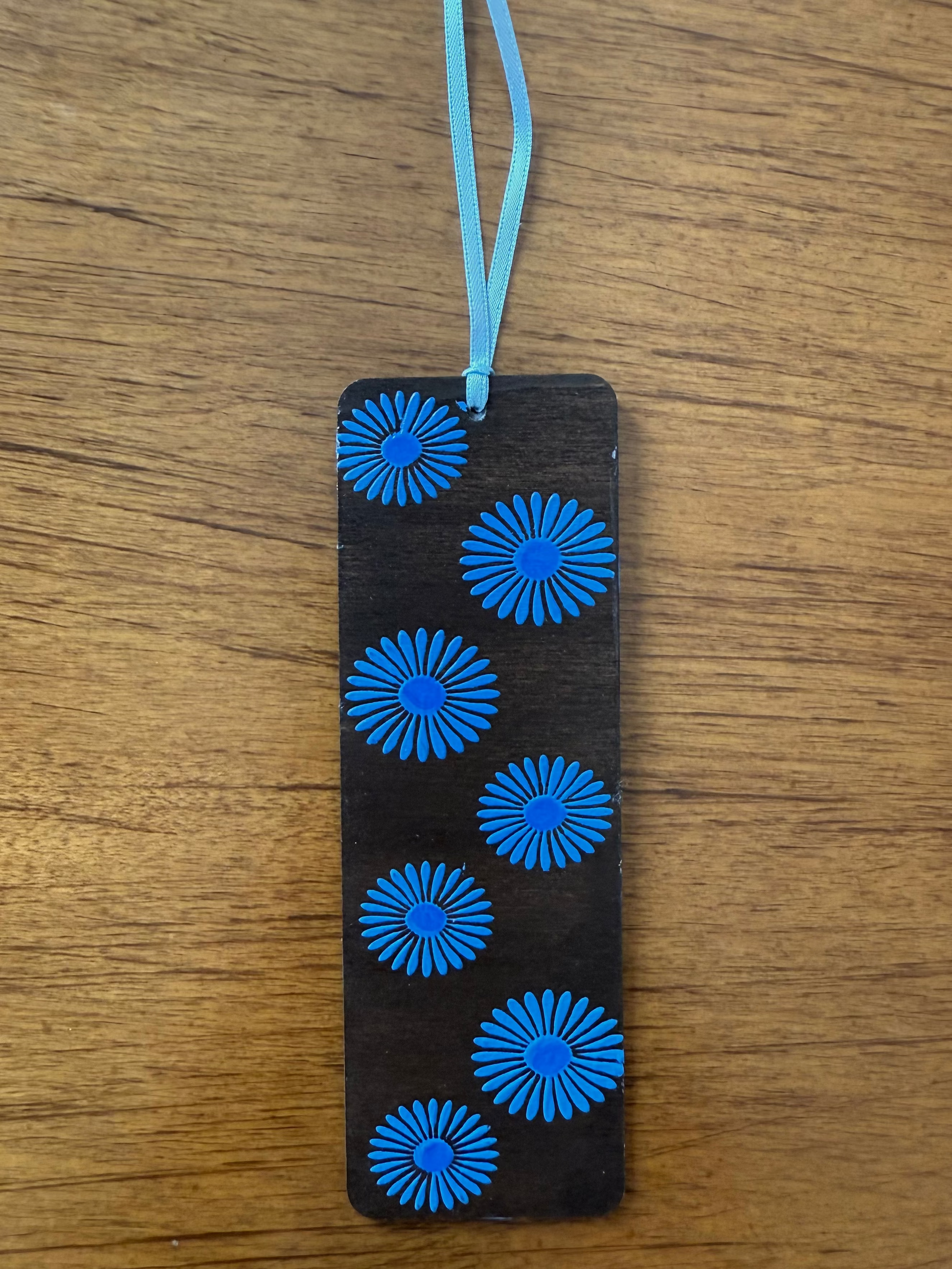 Black bookmark with blue floral patterns on a wooden surface