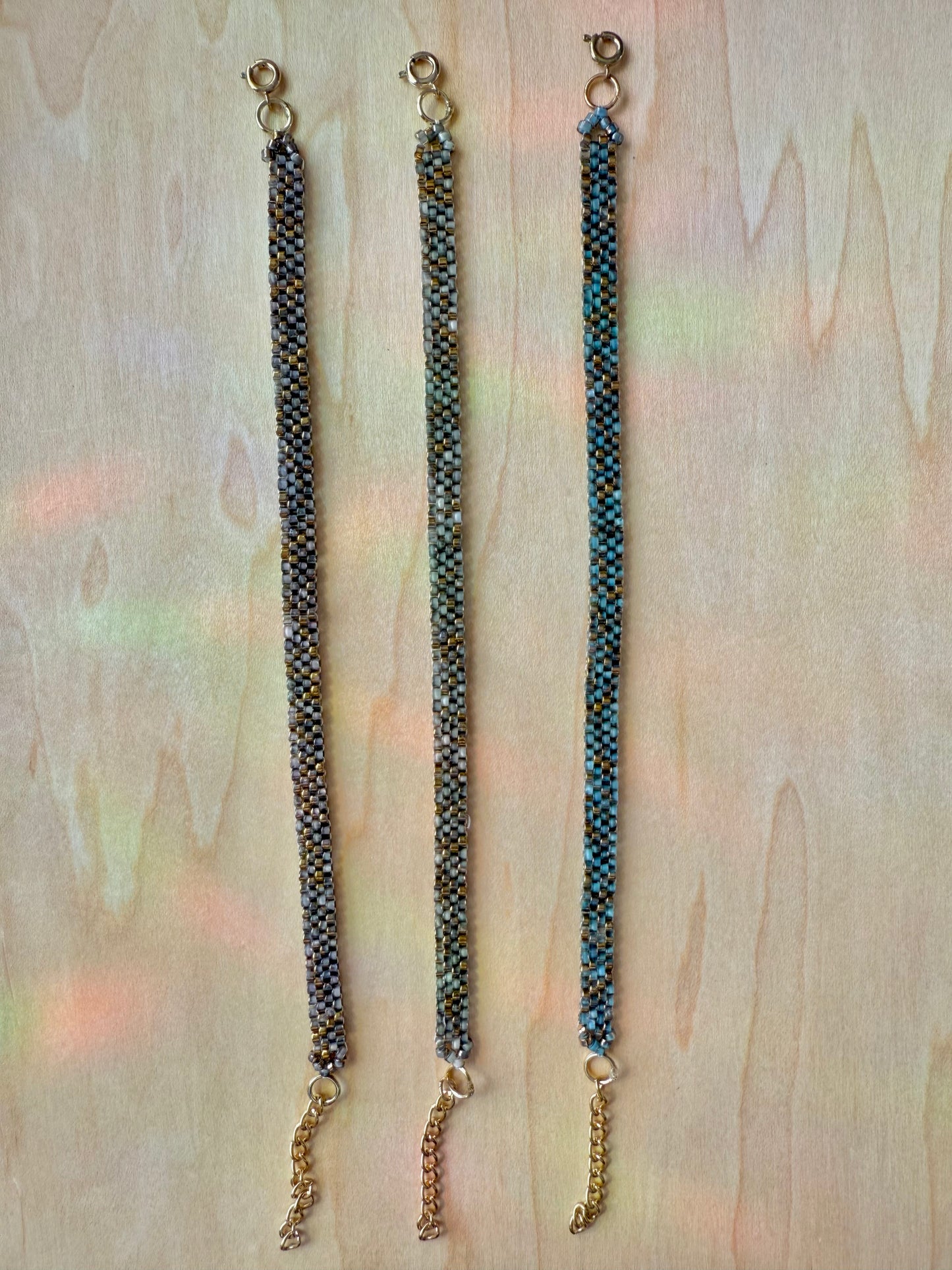 Three beaded bracelets on a wooden surface with a blurred background