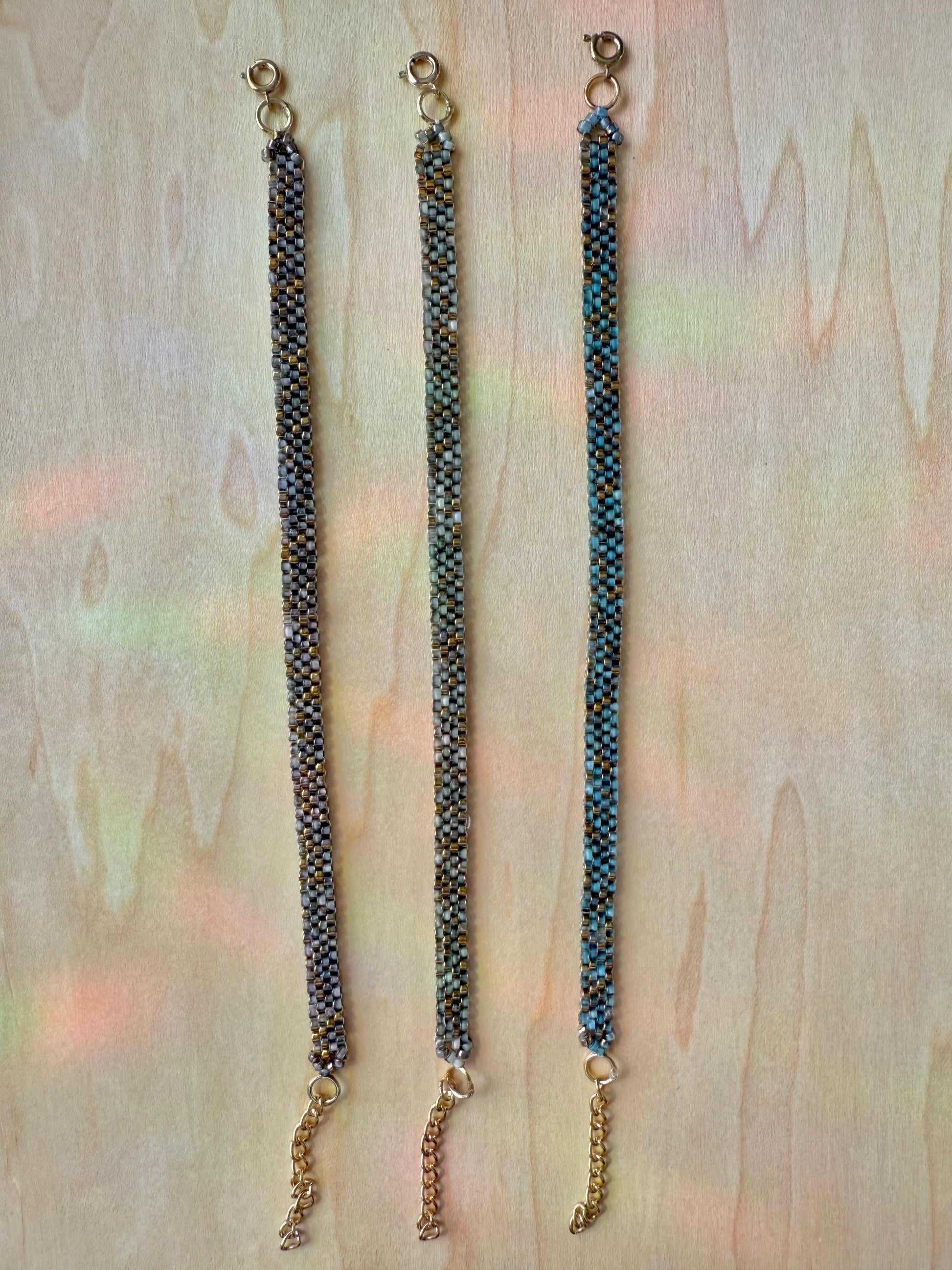 Three beaded bracelets on a wooden surface with a blurred background