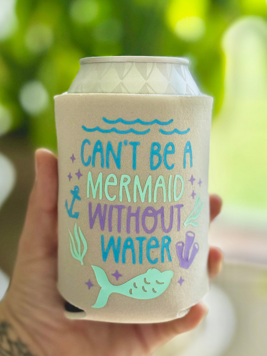 Can cooler with 'Can't be a mermaid without water' text held by a hand against a blurred green background