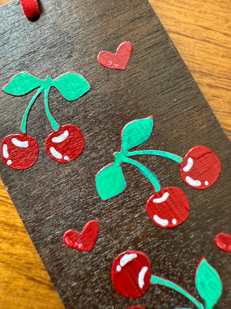 Bookmark of cherries and hearts on a wooden surface