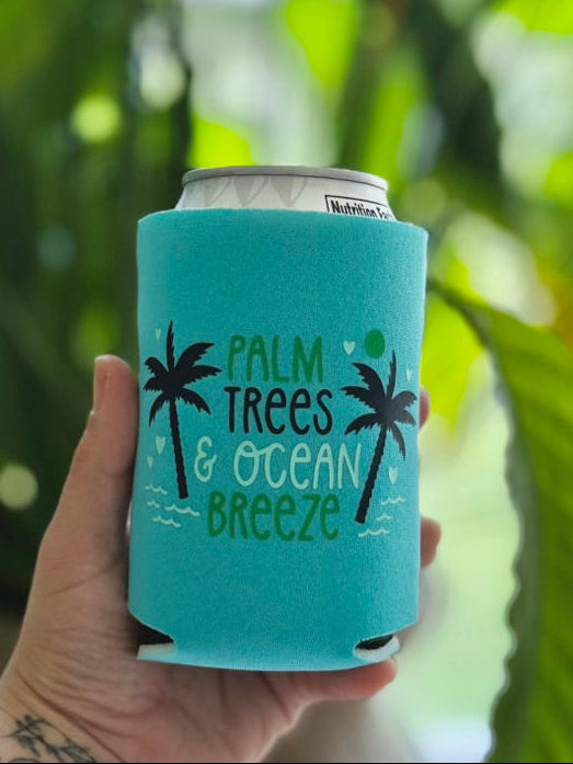 Turquoise can cooler with 'Palm Trees & Ocean Breeze' text held by a person with tattoos.