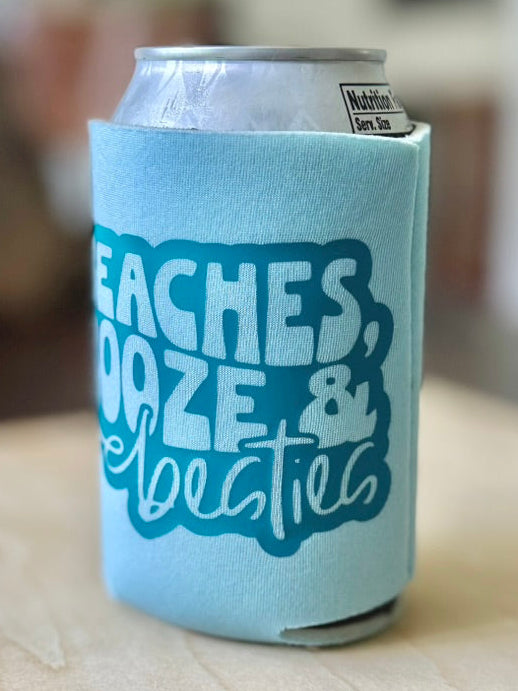 Can with a light blue sleeve featuring text on a wooden surface
