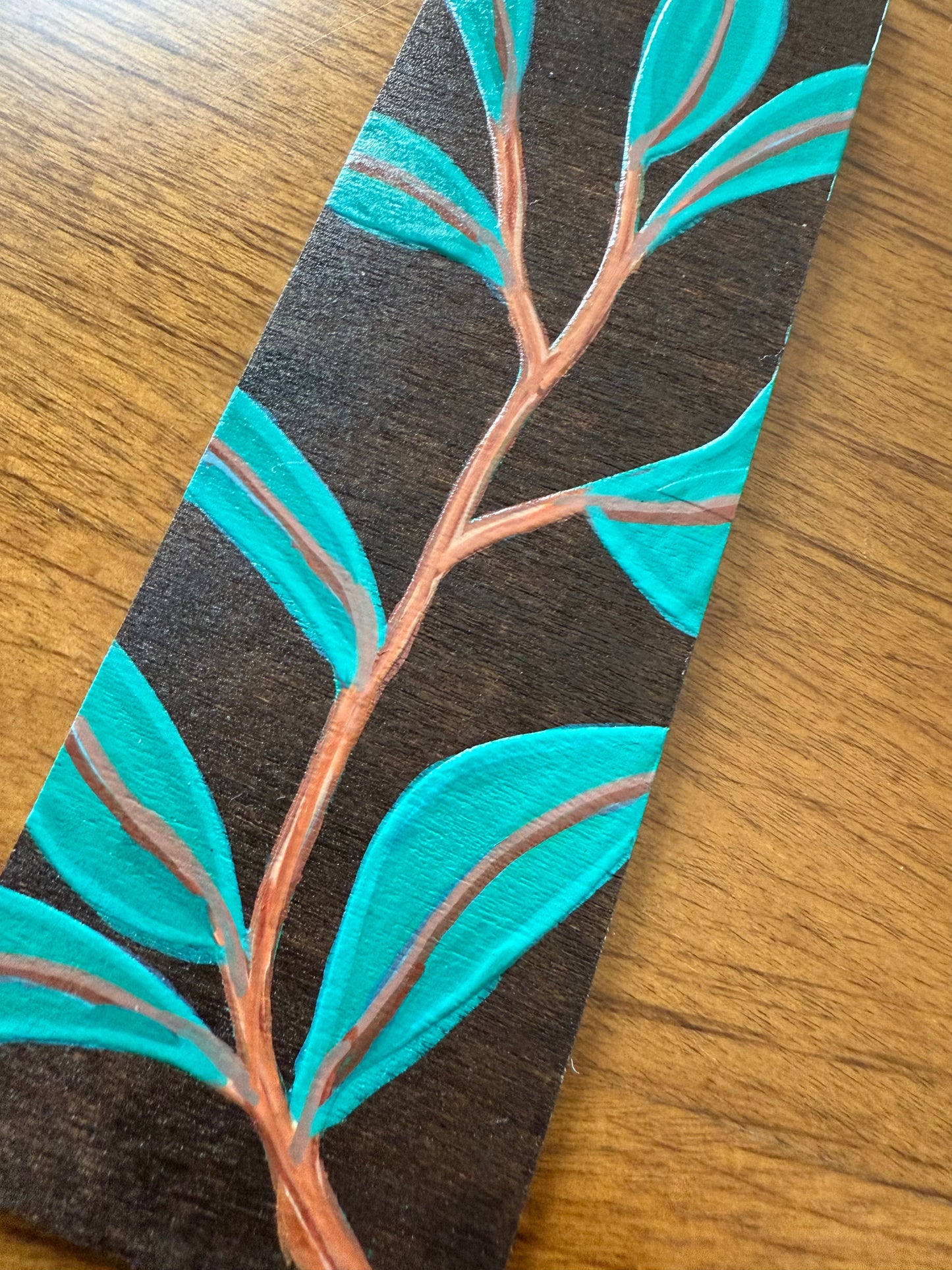 Wooden bookmark with a leaf pattern on a wooden surface