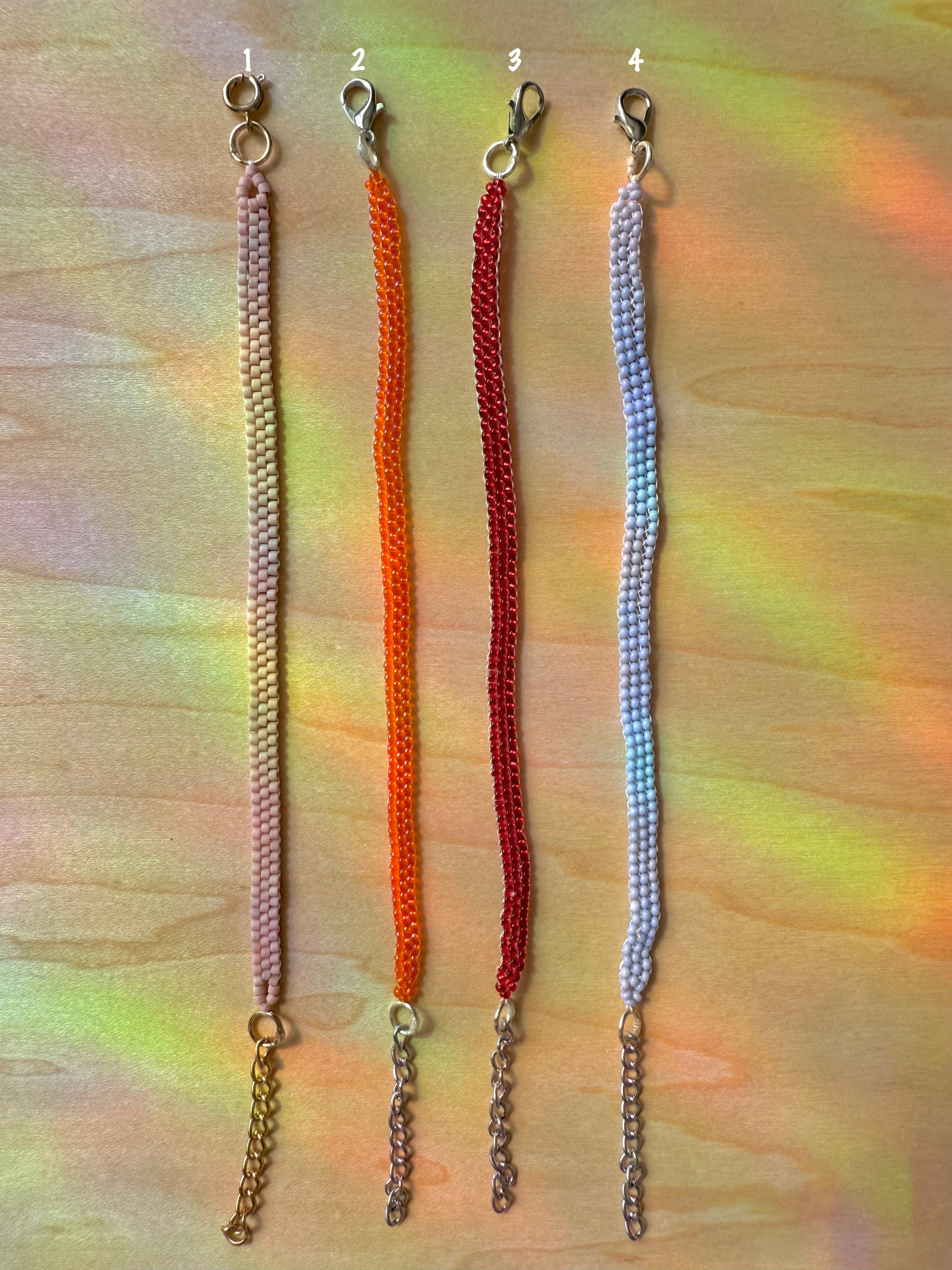 Four colorful beaded keychains on a multicolored background