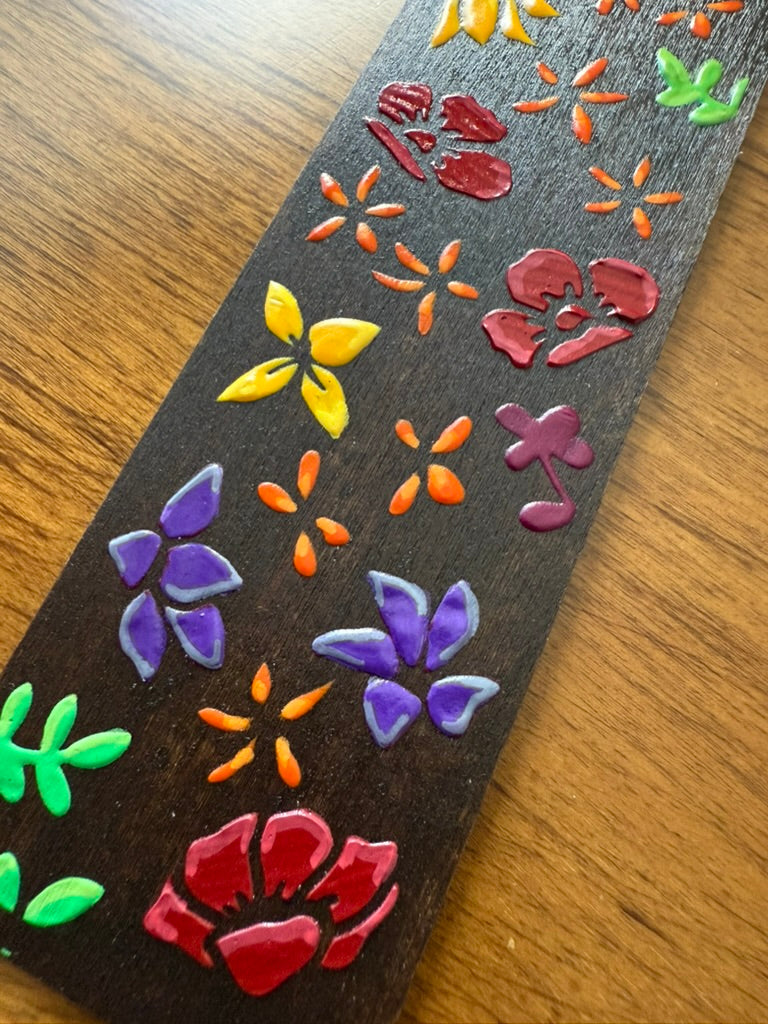 Decorative wooden object with colorful floral designs on a wooden surface