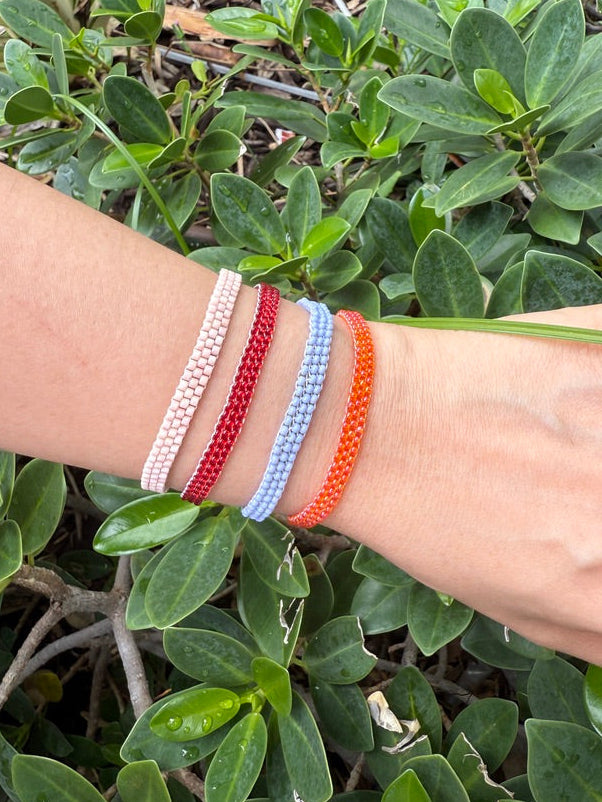 Wrist with colorful bracelets against a green leafy background