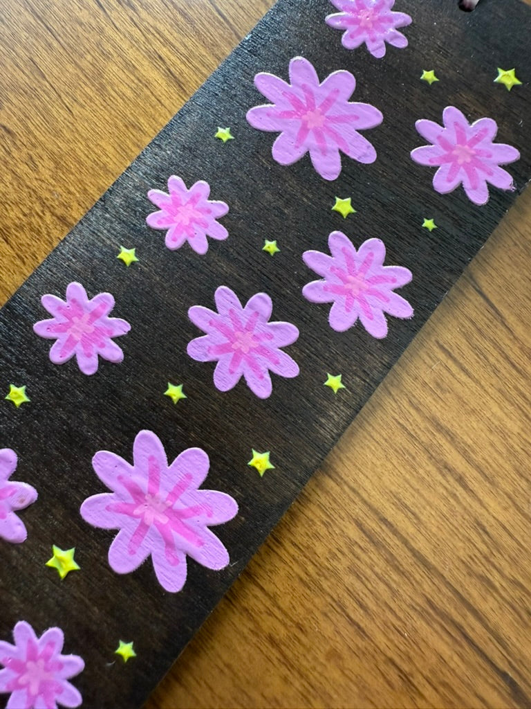 bookmark with pink flowers and yellow stars on a wooden surface