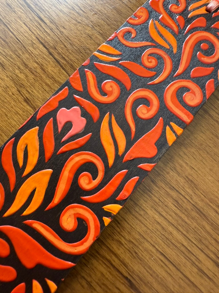Decorative bookmark with orange and black pattern on a wooden surface