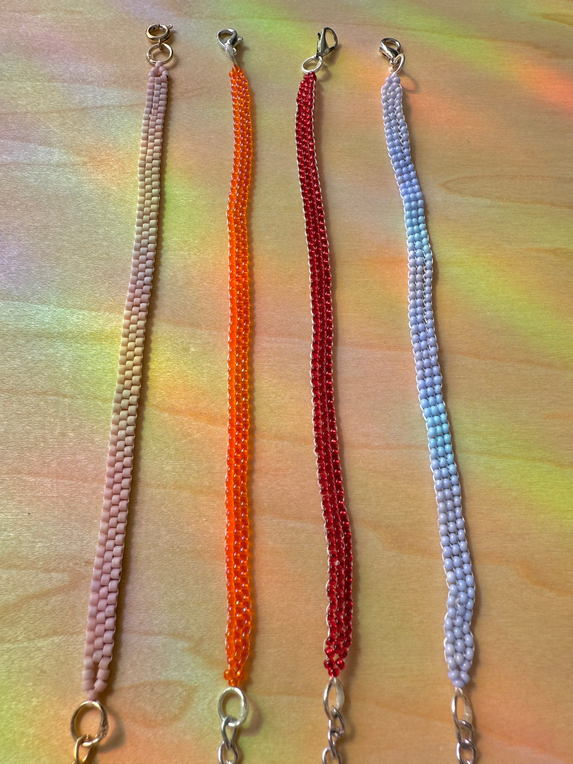 Four colorful chain necklaces on a multicolored background