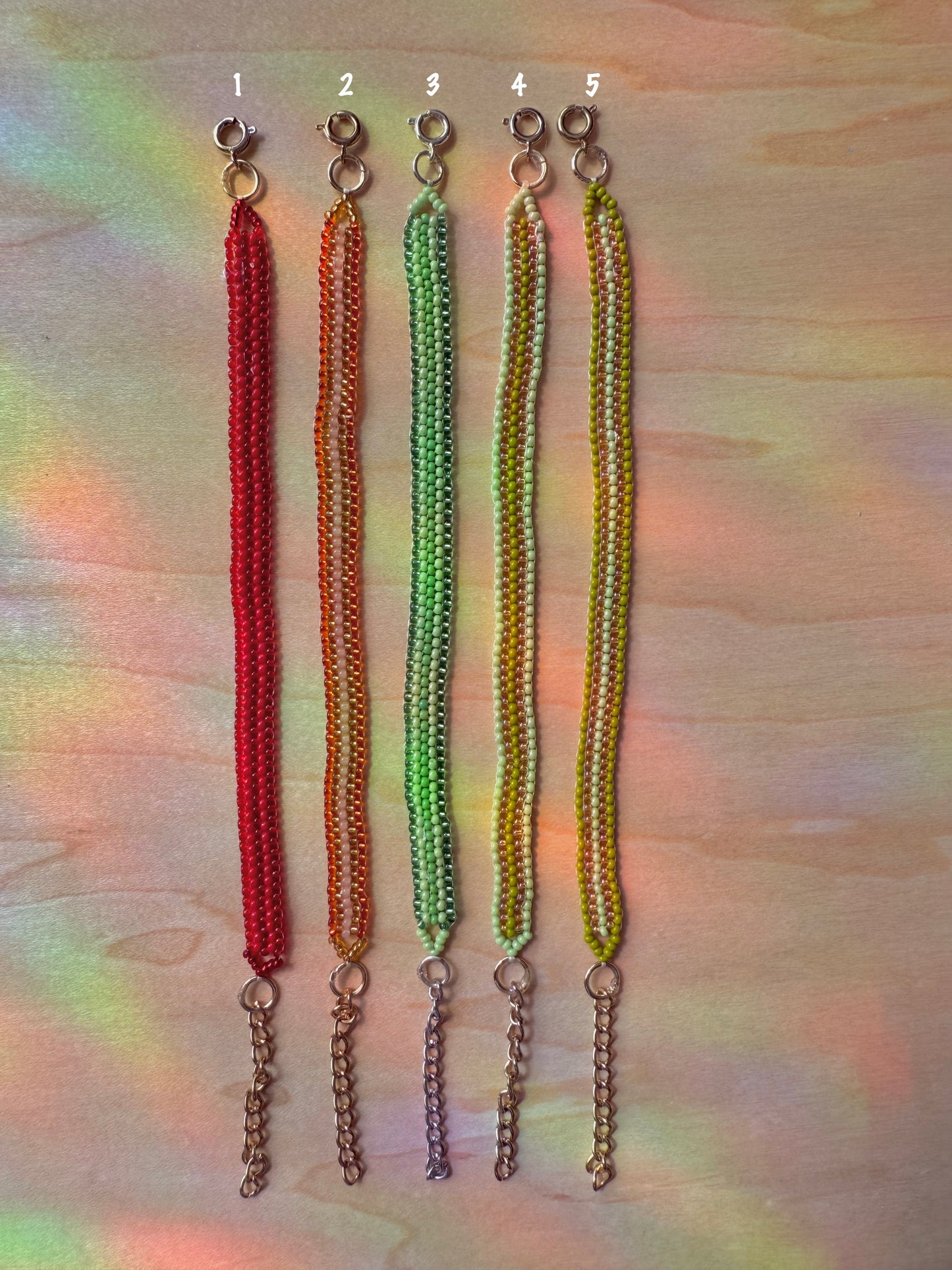 Five beaded keychains in red, orange, green, and yellow on a multicolored background.