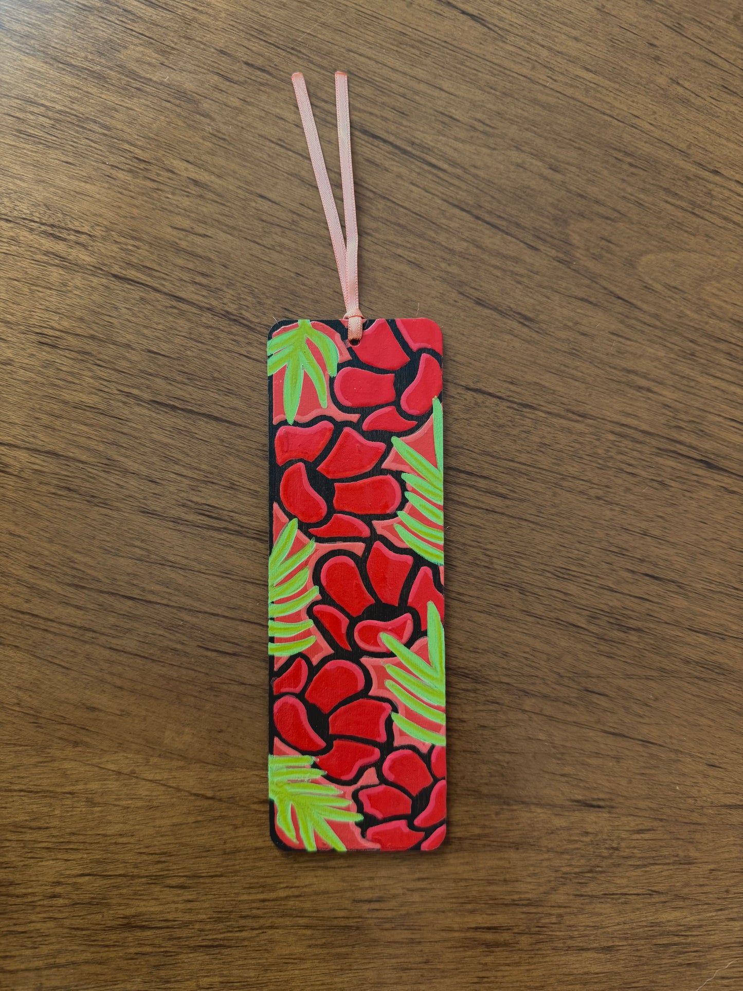 Rectangular bookmark with red floral pattern on a wooden surface