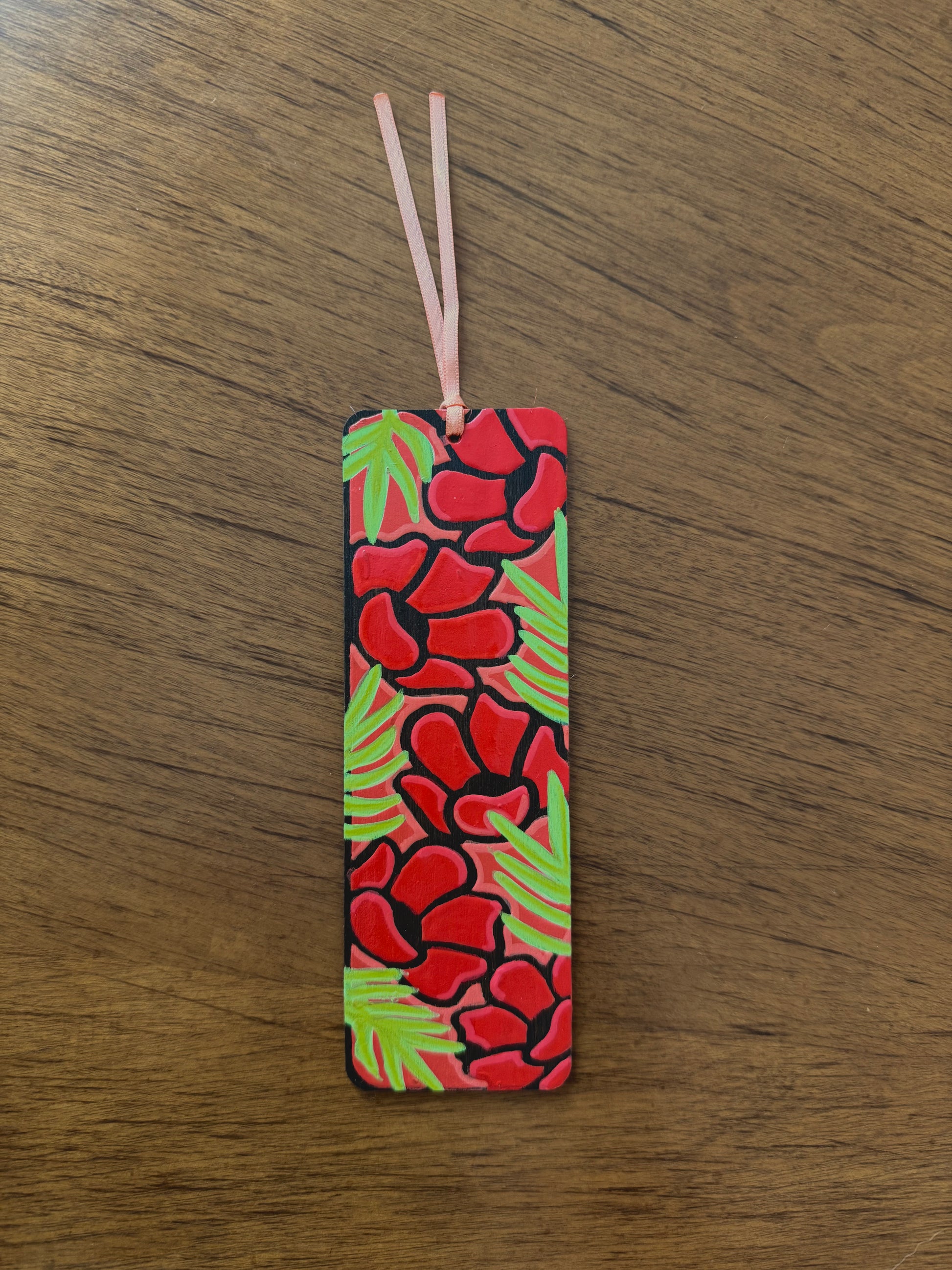 Rectangular bookmark with red floral pattern on a wooden surface