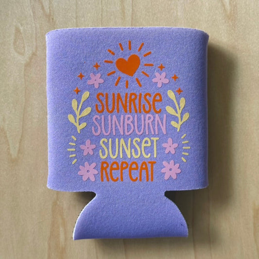 Purple can cooler with 'Sunrise Sunburn Sunset Repeat' text on a wooden surface