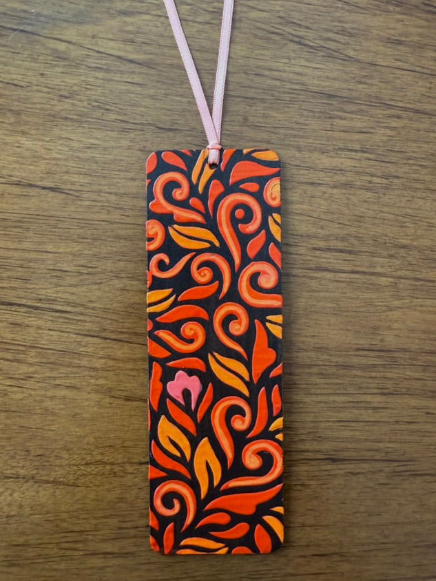 Decorative bookmark with orange and black pattern on a wooden surface