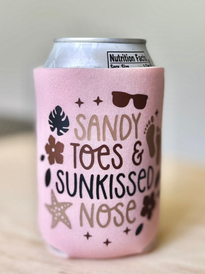Pink can cooler with 'Sandy Toes & Sunkissed Nose' text on a light background