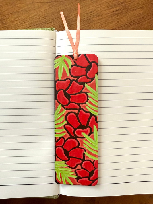 Colorful bookmark with red flowers and green leaves on an open book.