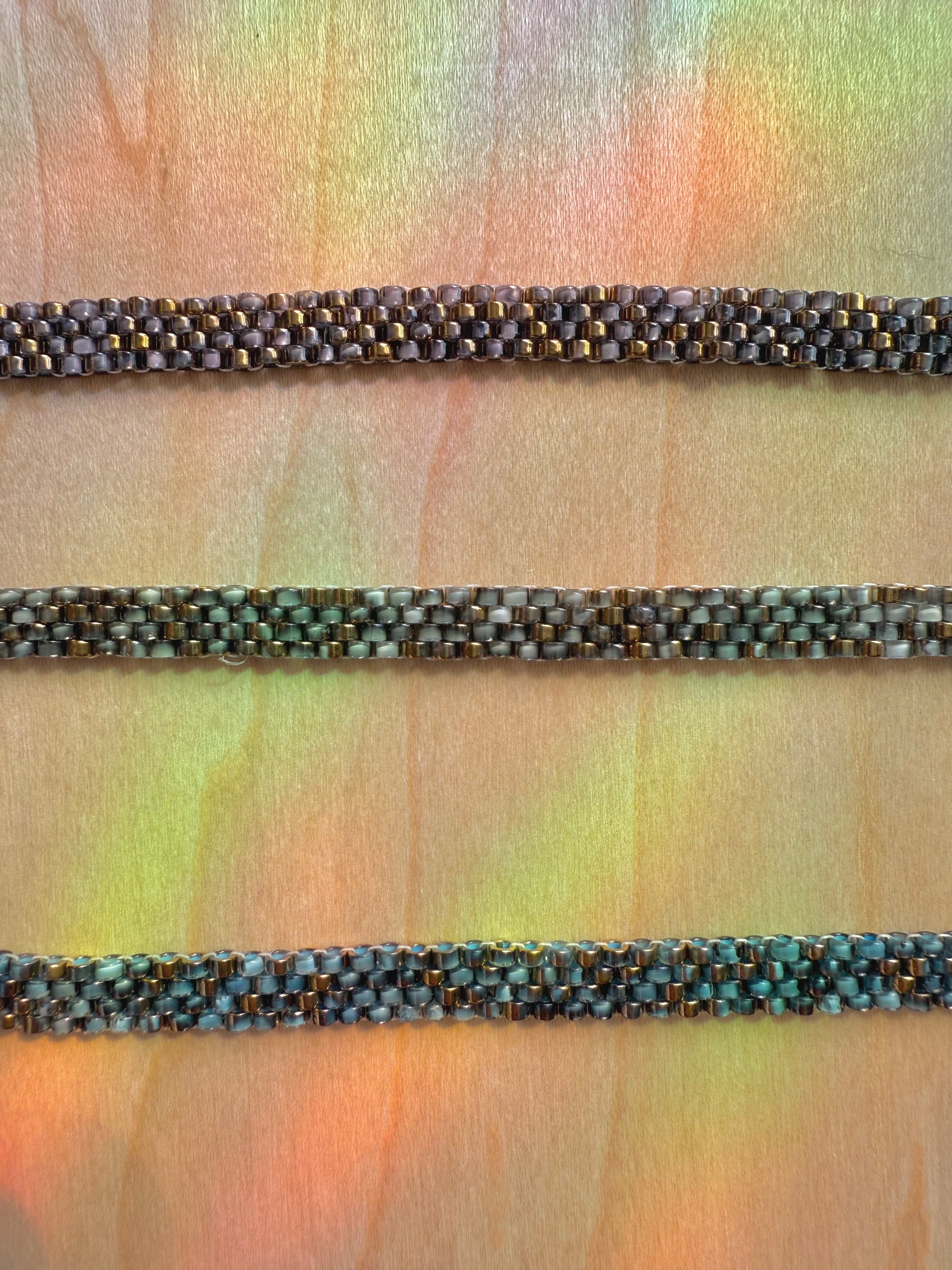 Three braided bracelets of different colors on a textured fabric background