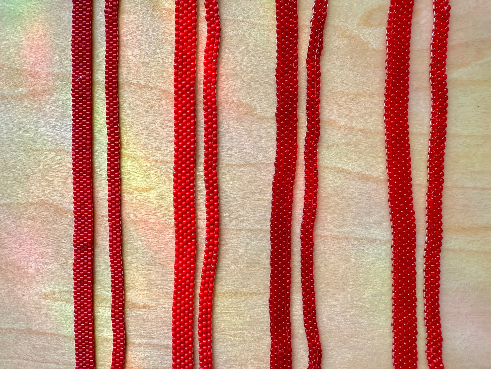 Close-up of red beaded strings on a textured beige background