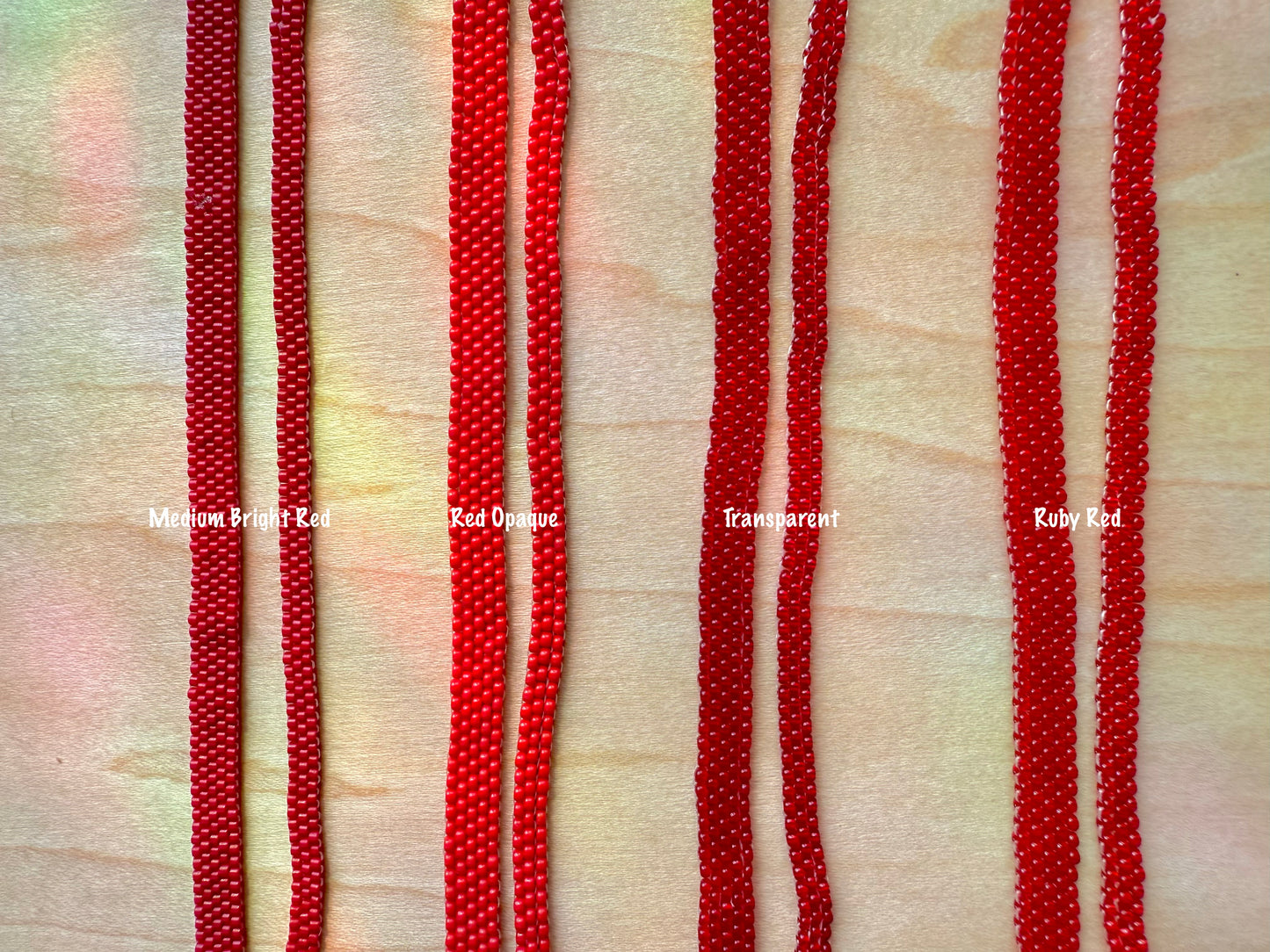 Red beaded strands on a textured beige background with color labels.