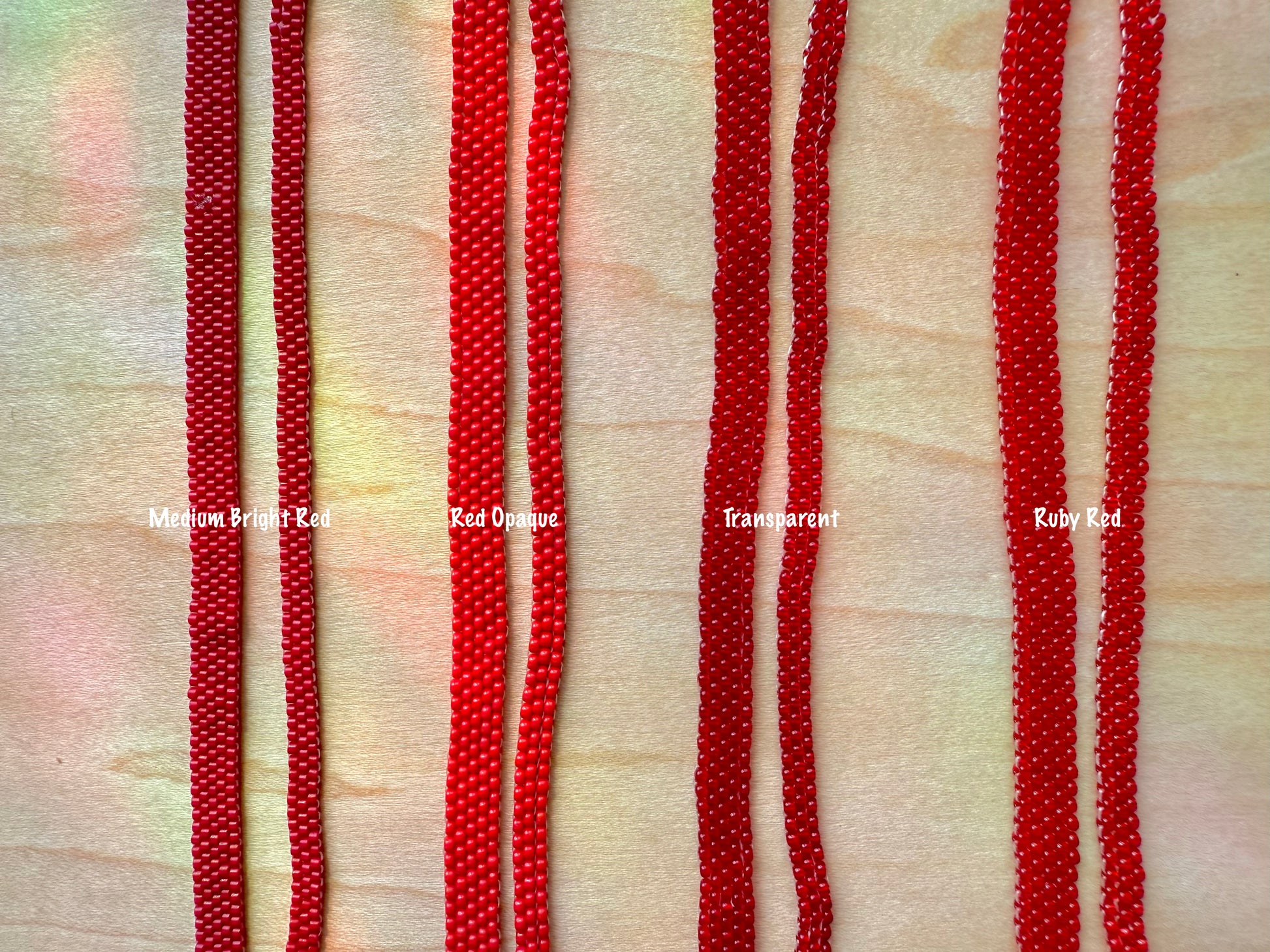 Red beaded strands on a textured beige background with color labels.