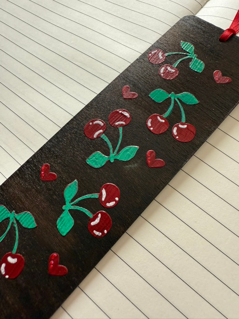 Dark bookmark with red cherries and green leaves on a lined notebook page