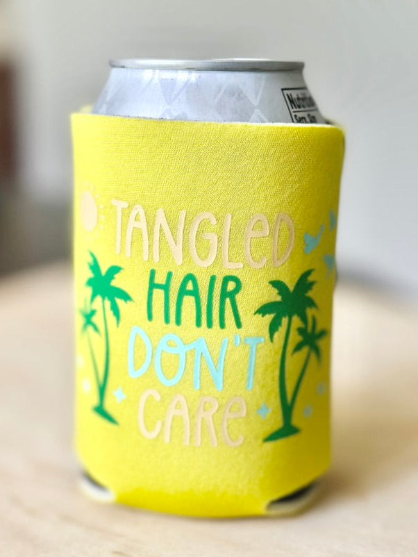 Yellow can cooler with 'Tangled Hair Don't Care' text and palm tree graphics on a wooden surface.
