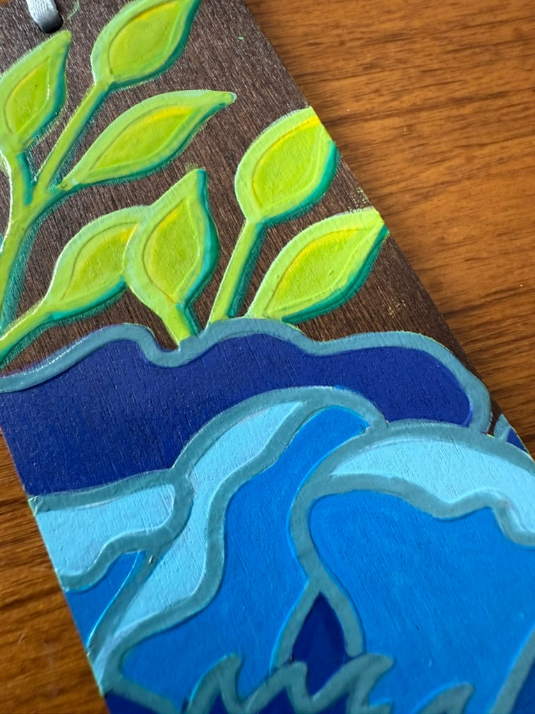 Artistic depiction of leaves and wavy blue patterns on a wooden surface