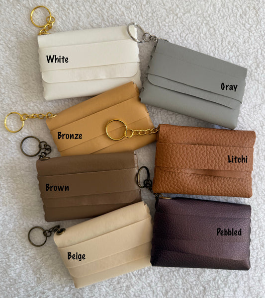 Collection of small wallets in various colors with labels on a textured white background