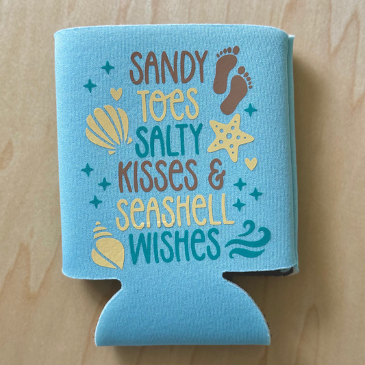 Blue can cooler with beach-themed text and graphics on a wooden surface