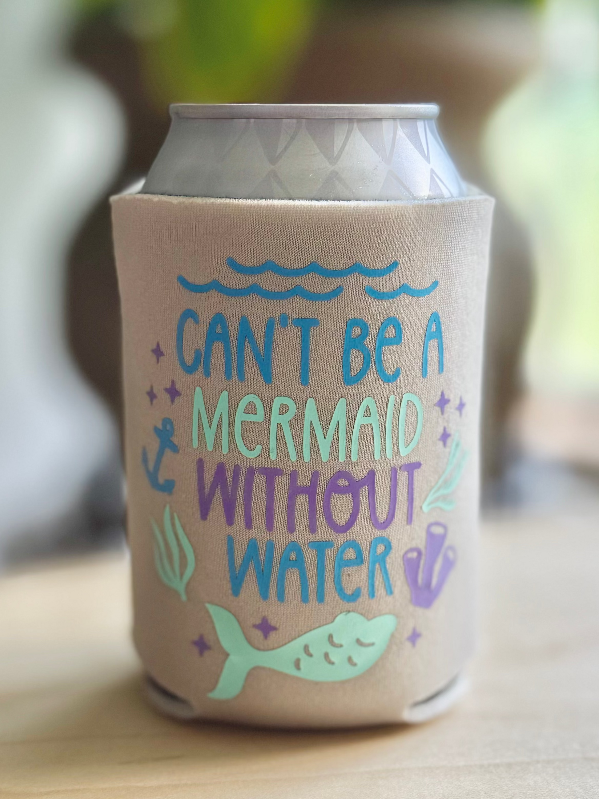 Can cooler with mermaid-themed design on a wooden surface