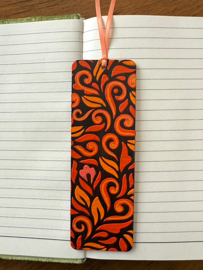 Decorative orange and black bookmark on a notebook with a wooden surface background