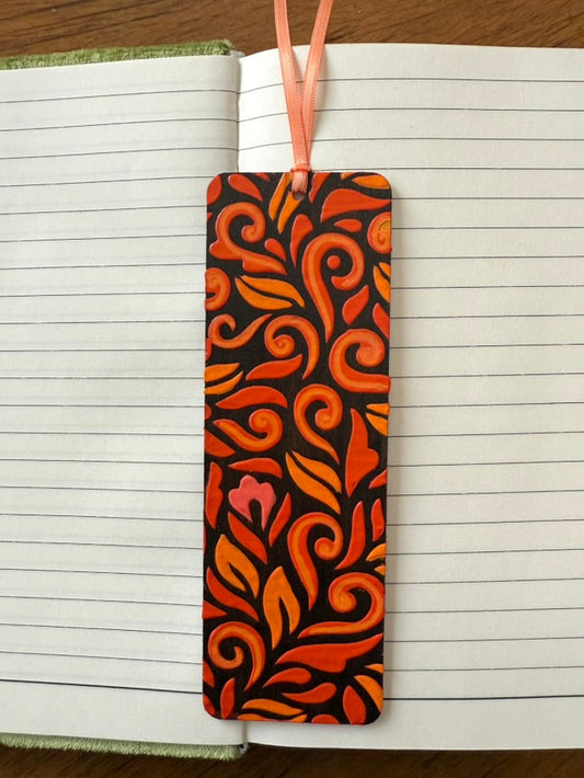 Decorative orange and black bookmark on a notebook with a wooden surface background