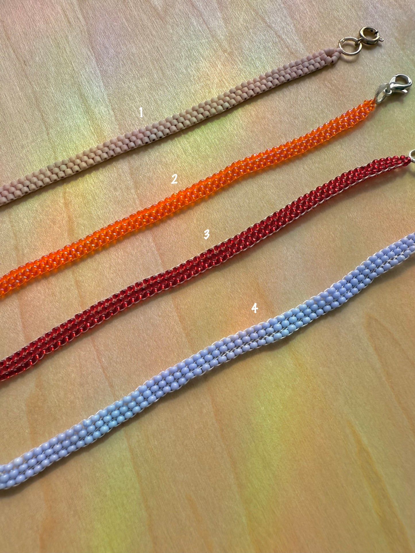 Four colorful beaded necklaces on a wooden surface