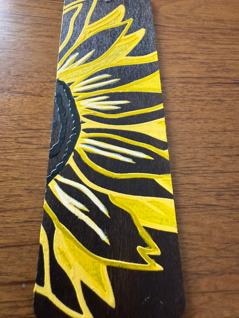 Black Bookmark with yellow floral design on a wooden surface