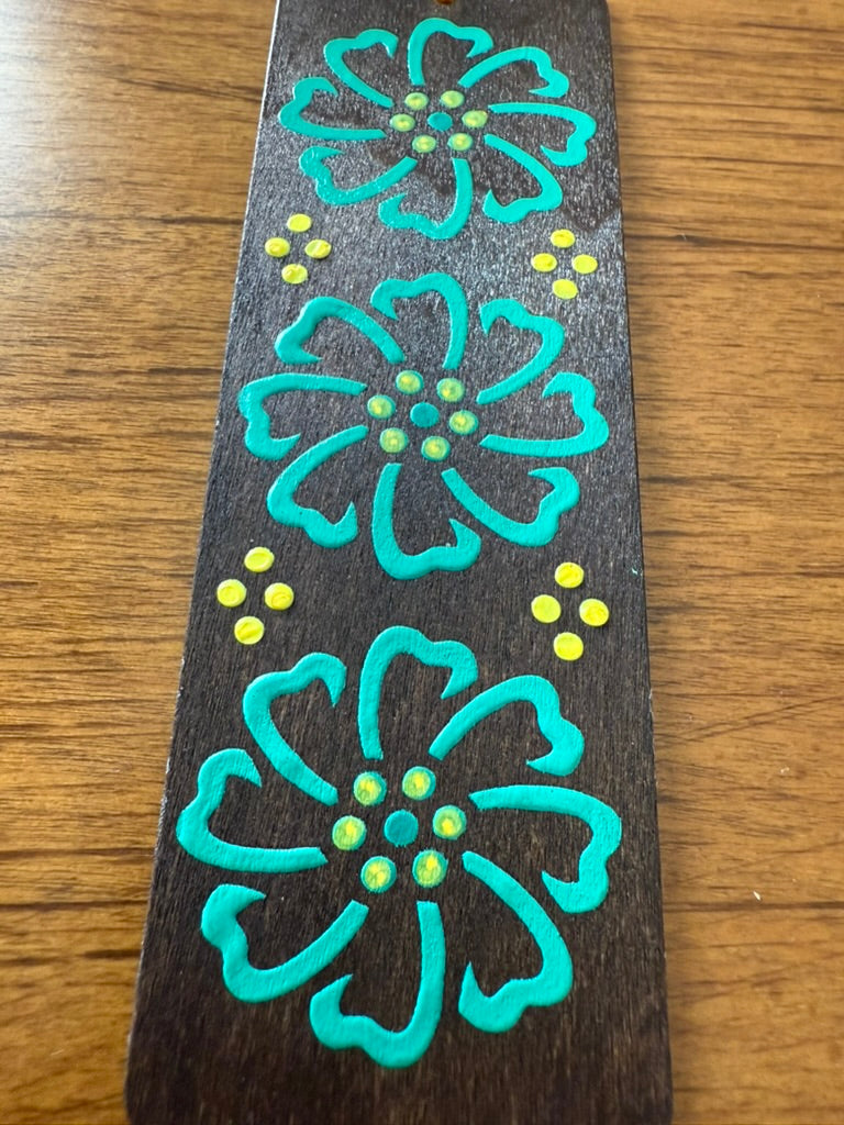 Decorative bookmark with turquoise floral designs on a wooden surface