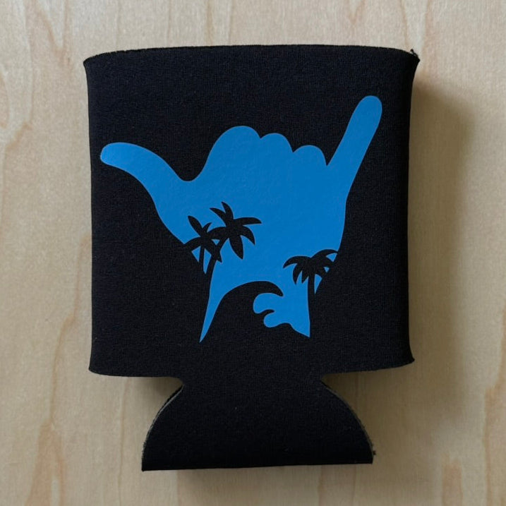 Black can cooler with blue 'hang loose' hand gesture design on a wooden surface