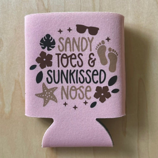 Pink can cooler with beach-themed design on a wooden surface