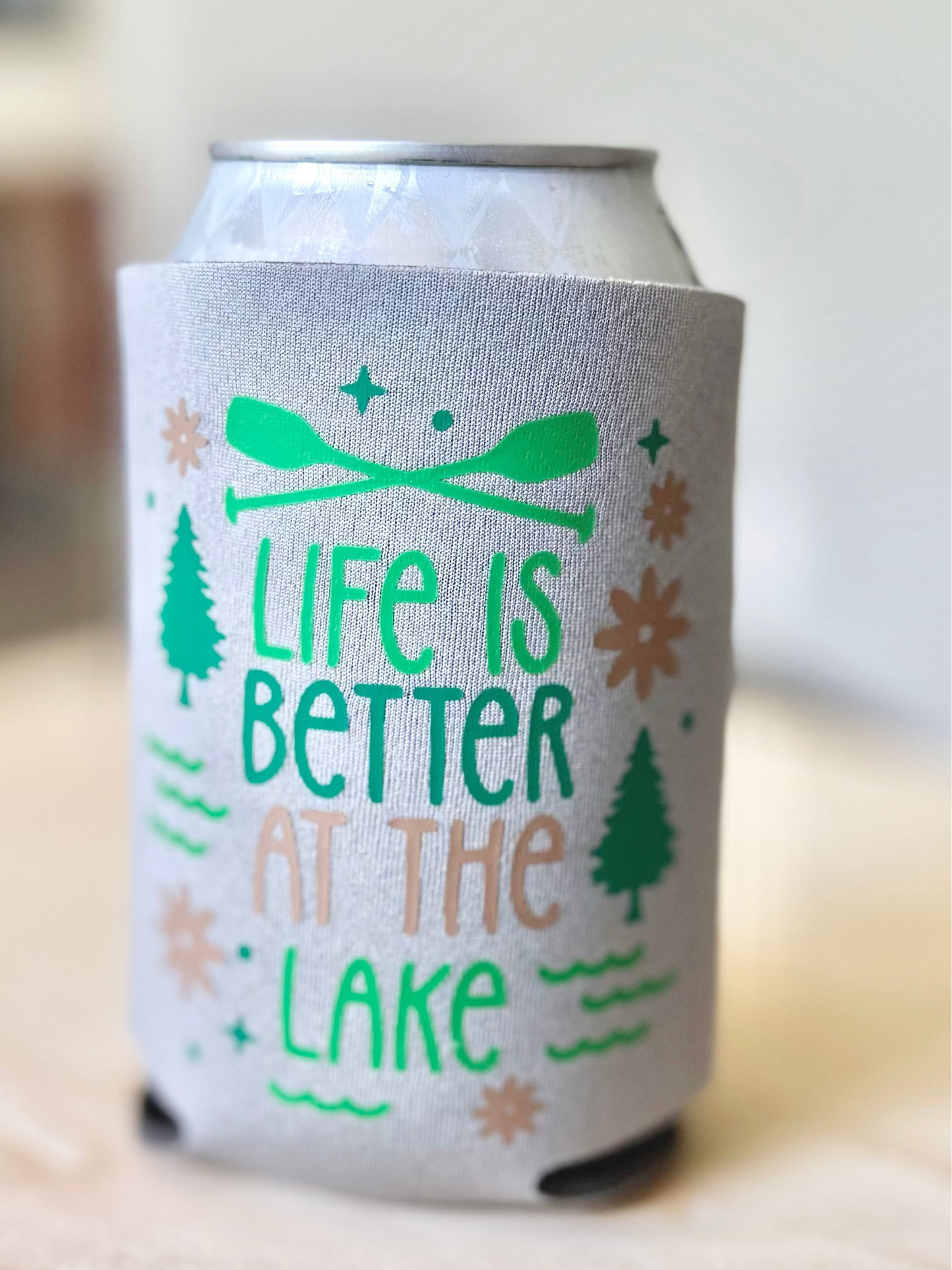 Can cooler with 'Life is Better at the Lake' text and graphics on a wooden surface