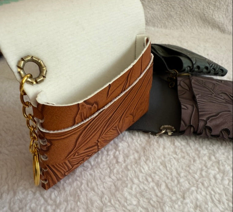 Brown leather wallet with gold chain and keychain on a textured surface
